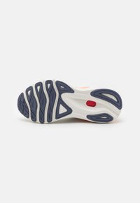 Semelle de chaussure avec un design en caoutchouc texturé. Principalement blanche avec des accents bleus et des détails rouges, comportant des rainures courbées pour une meilleure adhérence.
