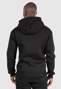 Sweatshirt à capuche noir avec une texture douce, doté de poignets et d'ourlet côtelés. L'arrière présente une coupe décontractée et un design sans couture.