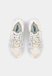 Baskets de course blanches et gris clair avec une tige en maille, une languette rembourrée et des lacets. Marquage Saucony notable sur les semelles intérieures et les côtés.