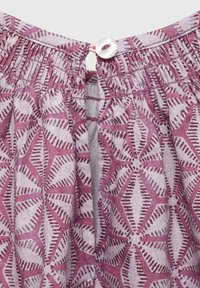 Tessuto a motivo viola e rosa con scollatura arricciata e dettaglio a bottone sulla schiena. Il design presenta forme geometriche e linee.