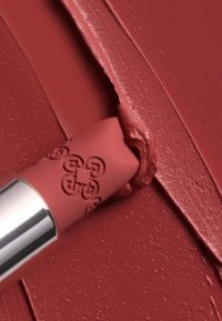 Matte läppstift i mjuk rosa, som avslöjar en krämig produkt. Slät textur med en lätt lyster, accentuerad av ingraverad logotyp och silverlock.