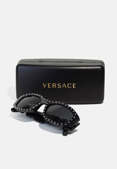 Black sunglasses with silver studs on the frame, accompanied by a sleek black case with "Versace" embossed in gold.