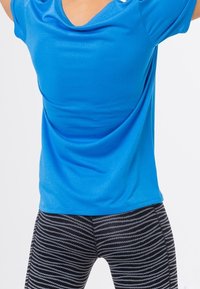 Camiseta deportiva azul de manga corta, combinada con mallas negras con estampado de franjas horizontales. Ambas prendas son ajustadas.