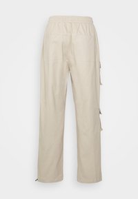 Beige Cargo-Hosen mit elastischem Bund, zwei Gesäßtaschen und seitlichen Knopfdetails. Gerades Bein Design mit glatter Textur.