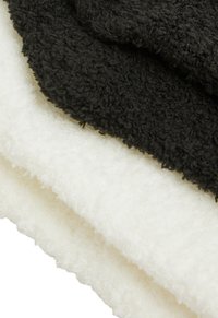 Asciugamani morbidi in bianco e nero, con una texture soffice. L'asciugamano nero è sovrapposto a quello bianco, mettendo in risalto i loro colori contrastanti.