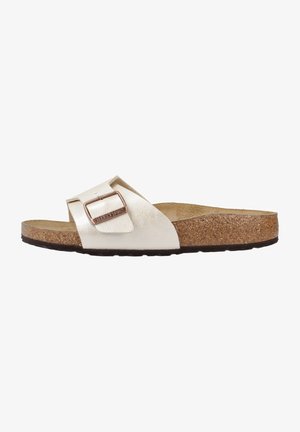 Birkenstock sandals with a wide, metallic, cream-colored leather strap, adjustable buckle, and a cork footbed with a textured black outsole.