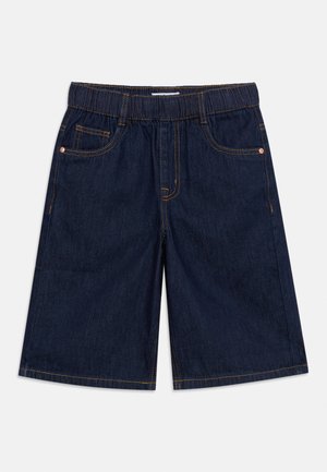 Tumesinised teksapüksid elastse vöökohaga, esimest zaded, oranži õmblusega, mõeldud igapäevaseks kandmiseks.