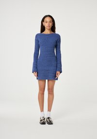 Gebreide blauwe jurk met een getailleerde silhoeet, lange mouwen en een bootnek. Heeft een gestructureerd patroon en eindigt tot halverwege het bovenbeen.