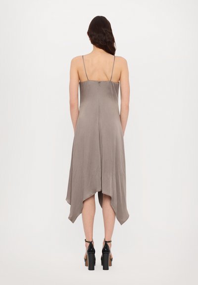 Satin gray dress with spaghetti straps, a fitted bodice, and an asymmetrical hemline. Styled with black heeled sandals.