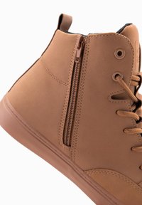 Hnědé syntetické vysoké tenisky s texturovaným povrchem, s bočním zipem a šněrováním, gumovou podrážkou a zesílenými švy.