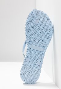 Sole of a light blue sandal with textured rope-like pattern and raised size markings for US 7, EUR 37, UK 4.