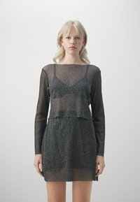 Abito nero trasparente a maniche lunghe con design cropped. Presenta un materiale testurizzato e luccicante e un top sottostante incorporato.