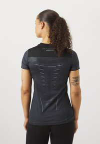 Svart atletisk skjorte med korte ermer, med teksturert design og reflekterende detaljer på ryggen for synlighet og pusteegenskaper.