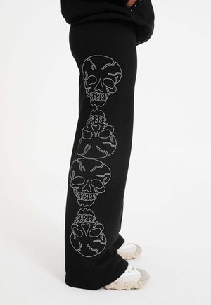 Black sweatpants featuring white skull graphics embroidered along the left leg. Made of soft material with a loose fit.
