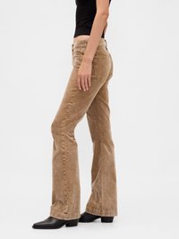 Brown corduroy flared pants with a textured surface, mid-rise waist, and classic five-pocket design. Paired with black ankle boots.
