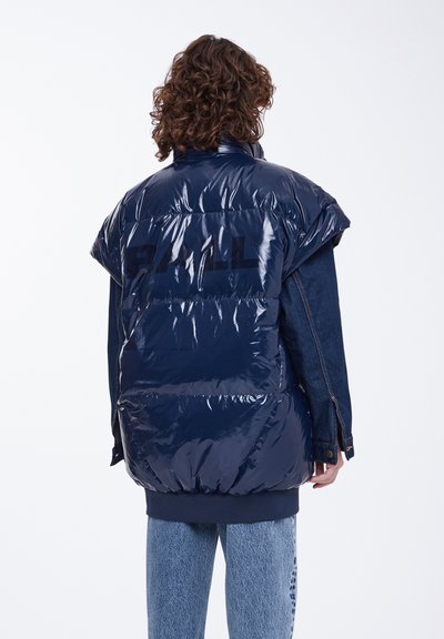 Tamsiai mėlynas pūkinis švarkas su blizgiu paviršiumi, per didelio dizaino ir ryškiais petimi. Yra tamsiai džinsiniai rankovės ir logotipas ant nugaros.