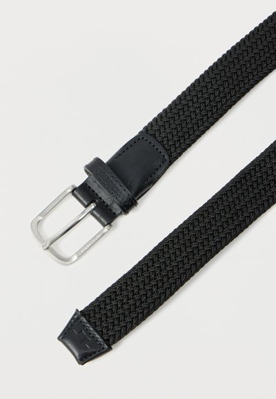 Μαύρη πλεκτή υφασμάτινη ζώνη με ασημένια μεταλλική αγκράφα και μαύρες δερμάτινες λεπτομέρειες στην αγκράφα και στην άκρη, απλωμένη επίπεδα σε λευκό φόντο.