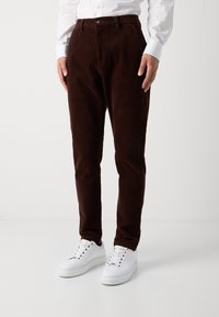 Bruna kordbyxor med rak skärning, med en knappstängning, bältesöljer och sidofickor, kombinerat med vita sneakers.