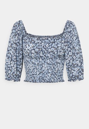 Sinine ja valge lillemustriga pluus, ruudukujulise kaelusega, smokk-kere ja puhvvarrukatega, valmistatud kergest kangast.