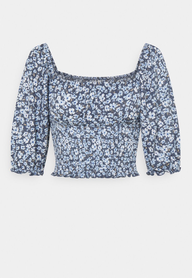 Blommönstrad topp i blått och vitt, med fyrkantig halsringning, smockad liv och puffärmar, tillverkad av lättviktig tyg.