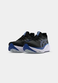 Baskets de sport noires avec des accents bleus, présentant un dessus texturé, un bout rond et une semelle intermédiaire blanche épaisse pour un amorti.