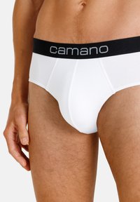 Weiße Baumwollunterhosen mit einem schwarzen elastischen Bund, der "camano" in grauer Schrift trägt. Der Stoff ist glatt und hat ein körpernahes Design.