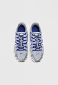 Nike atletske tenisice u sivoj mrežici s plavim detaljima. Imaju podstavljeni rub, vezivanje na vezice i strukturiranu gumenu potplate.