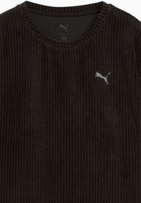 Zwarte corduroy sweatshirt met geribbelde textuur, ronde halslijn en klein wit Puma-logo op de linkerkant van de borst.