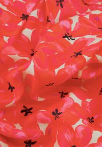 Satijnen stof met een levendige koraalachtergrond en grote roze bloemmotieven en zwarte accenten, waardoor een gedurfde en dynamische visuele uitstraling ontstaat.