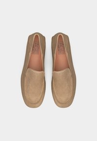 Ζευγάρι μπεζ μοκασίνια από σουέντ με ραμμένες στρογγυλεμένες τετράγωνες μύτες, ορατές εσωτερικές σόλες και ετικέτες της μάρκας "AGL".