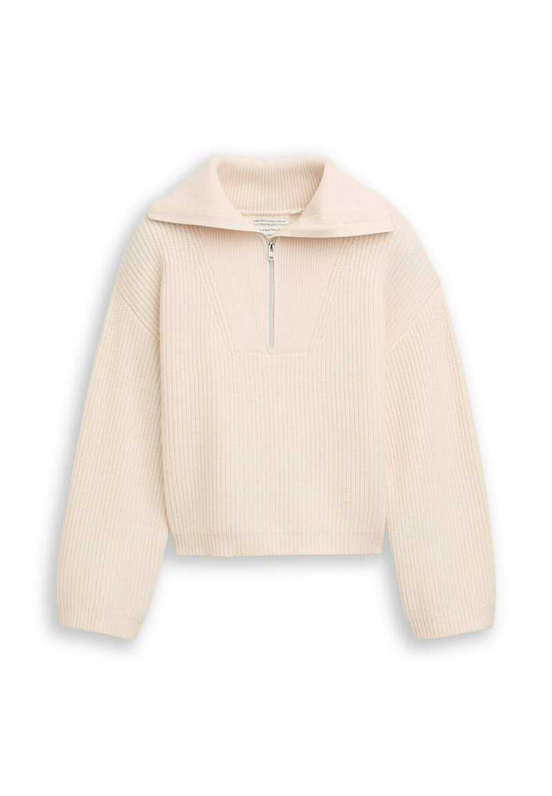 Helles beige, kurz geschnittenes Oberteil mit Rippenstruktur, halbseitigem Reißverschluss und breitem Kragen. Lange Ärmel und ein strukturiertes Design. Auffällige V-förmige Naht.