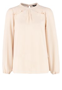Blouse crème à manches longues avec encolure ronde, détail à volants près des épaules, pli au centre devant et poignets élastiques.