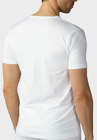Biała koszulka z krótkim rękawem wykonana z miękkiego materiału, z okrągłym dekoltem i dopasowanym krojem, o gładkiej fakturze i minimalnych detalach.