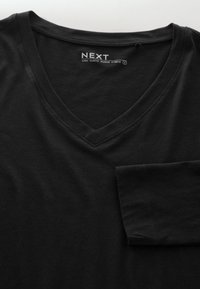 Czarna koszulka z długim rękawem i dekoltem w kształcie litery V, wykonana z miękkiego materiału, z kieszenią z przodu oraz przeszyciami przy dekolcie i krawędziach rękawów.