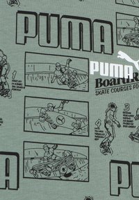 Tela verde con dibujos en línea negra de escenas de skate y instrucciones, con "PUMA" exhibido de manera prominente en letras negritas.