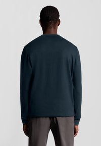 Långärmad mörkblå sweatshirt i mjukt material, med rund halsringning och avslappnad passform, visad bakifrån.
