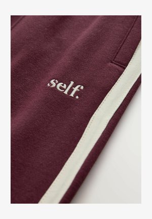 Maroon sweatpants with white side stripes and embroidered logo "self." near the pocket. Soft material with a smooth texture.