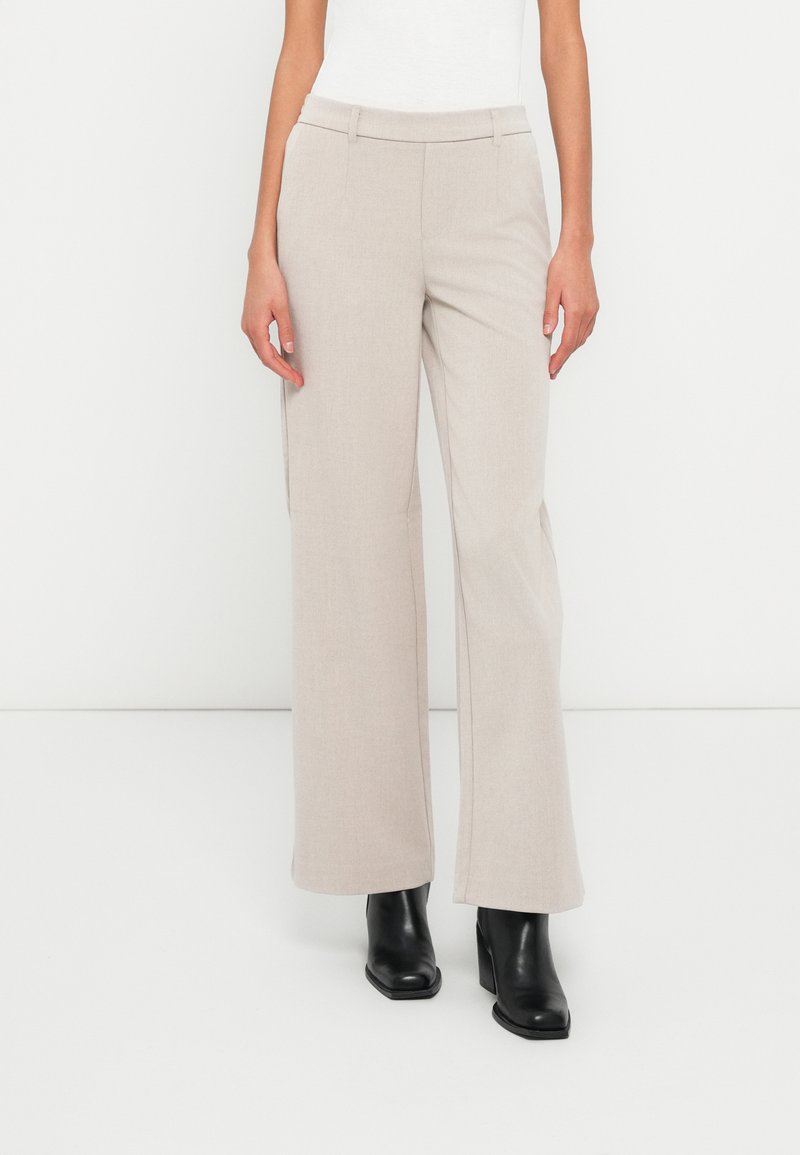 Light beige wide-leg trousers made of textured fabric with a subtle pattern, featuring a fitted waistband and side pockets.