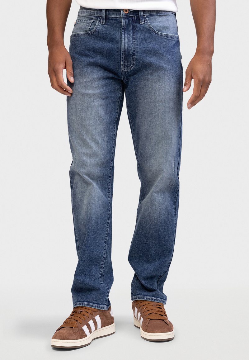 Σκούρο μπλε τζιν με κλασικό σχέδιο, που διαθέτει ίσια γραμμή, ξεβαμμένες λεπτομέρειες, πέντε τσέπες και ραμμένες λεπτομέρειες.