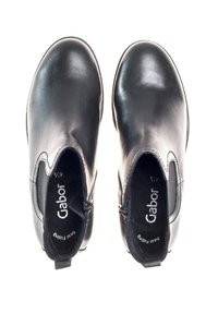 Botines negros, material de cuero suave, diseño curveado, cremalleras laterales, forro interior suave, suela plana con un mínimo de relieve.