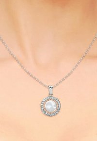 Collana d'argento con un pendente rotondo che presenta una perla bianca centrale circondata da una cornice circolare di gemme scintillanti.