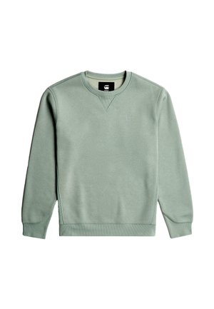 Világoszöld, kerek nyakú pulóver puha anyagból. Bordás mandzsettákkal, szegéllyel és egy kis logóval a mellkason. Simább textúra.