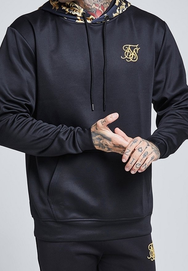 Sudadera con capucha negra con logo dorado, textura suave y capucha con diseño en el interior. Cuenta con un bolsillo delantero y cordones.
