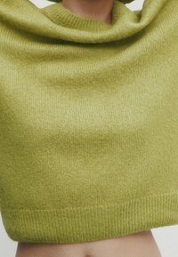 Crop top en tricot de couleur vert vif, avec un col bénitier, une texture douce et un ourlet côtelé. Le tissu semble léger et confortable.