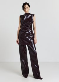 Weinrotes, glänzendes zweiteiliges Outfit mit einem ärmellosen Oberteil mit hohem Kragen und weiten Hosen mit glatter, reflektierender Oberfläche.