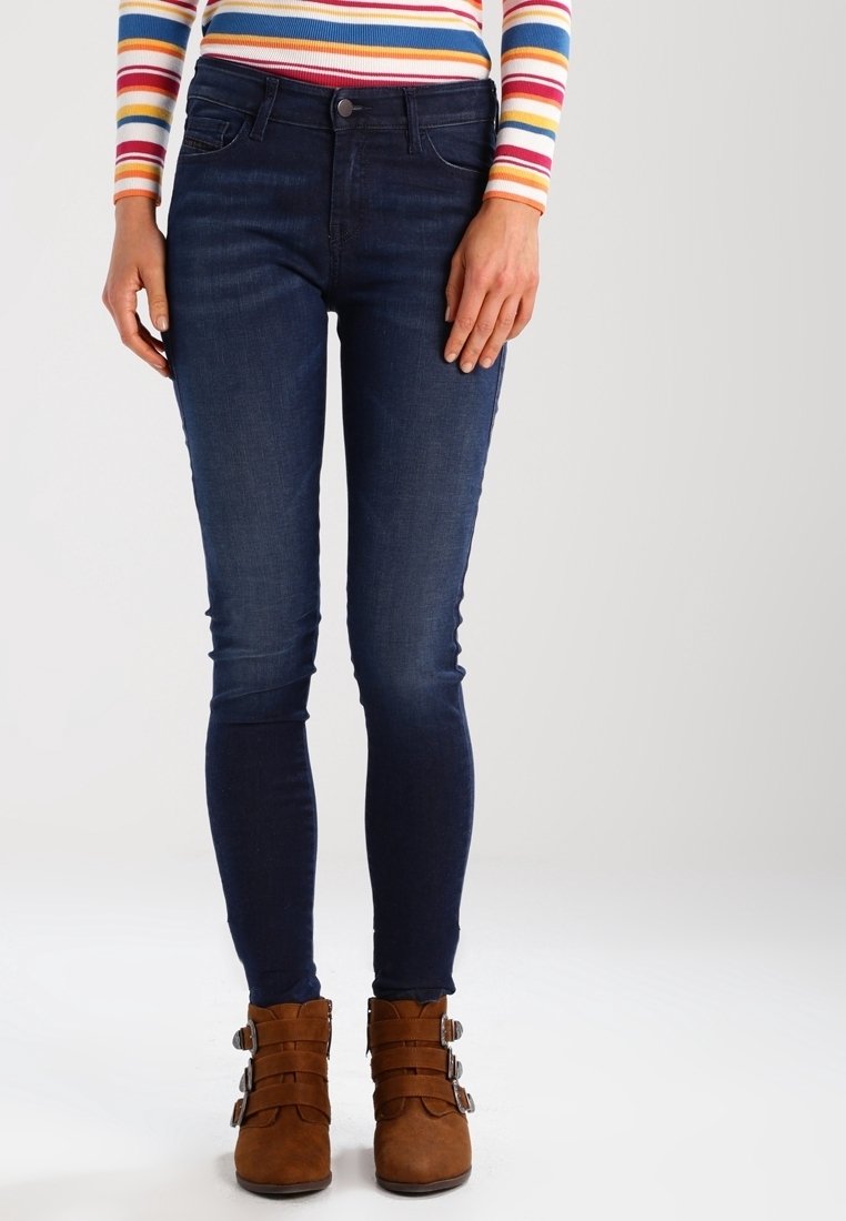 Mörkblå skinny jeans i denim med en slät yta, tillsammans med bruna ankelboots med flera spännen.