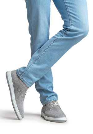 Grijze gestreepte sneakers met een bovenwerk van een gestructureerde stof, een lichte rubberen zool en beige veters, gecombineerd met lichtblauwe spijkerbroeken.