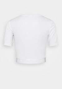 Bílý zkrácený tričko s krátkým rukávem, vyrobené z hladké tkaniny. Obsahuje texturovaný bílý logo pásek na spodním lemu.