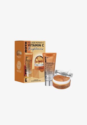 Vitamine C huidverzorgingsset in oranje verpakking. Bevat een scrubtube en een pot hydrogel oogmaskers met een gouden tint en accentdetails.