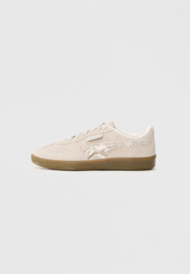 Beige suede sneaker with a textured side accent, lace closure, and rubber sole. Subtle sheen on decorative elements. Smooth finish.